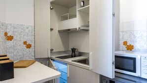 Una cocina compacta con microondas integrado, cafetera y lavabo.