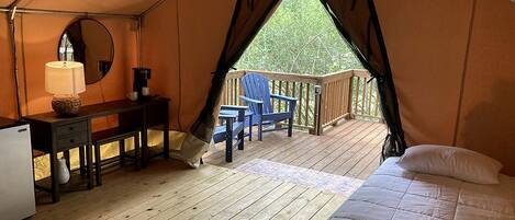 A tent with a bed, desk, chair, and a small table.