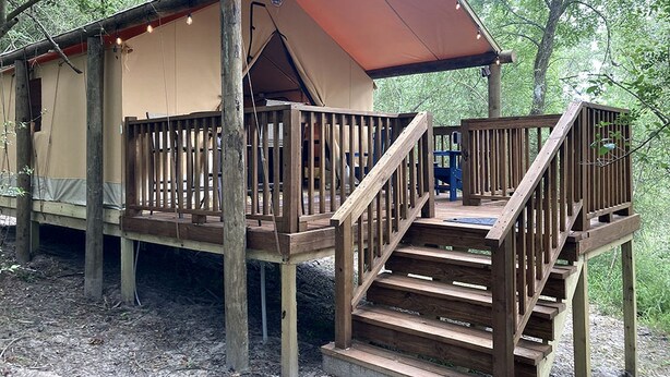 Eine Holzdielen-Terrasse mit einer Treppe, die zu einem überdachten Bereich mit rotem Dach führt.