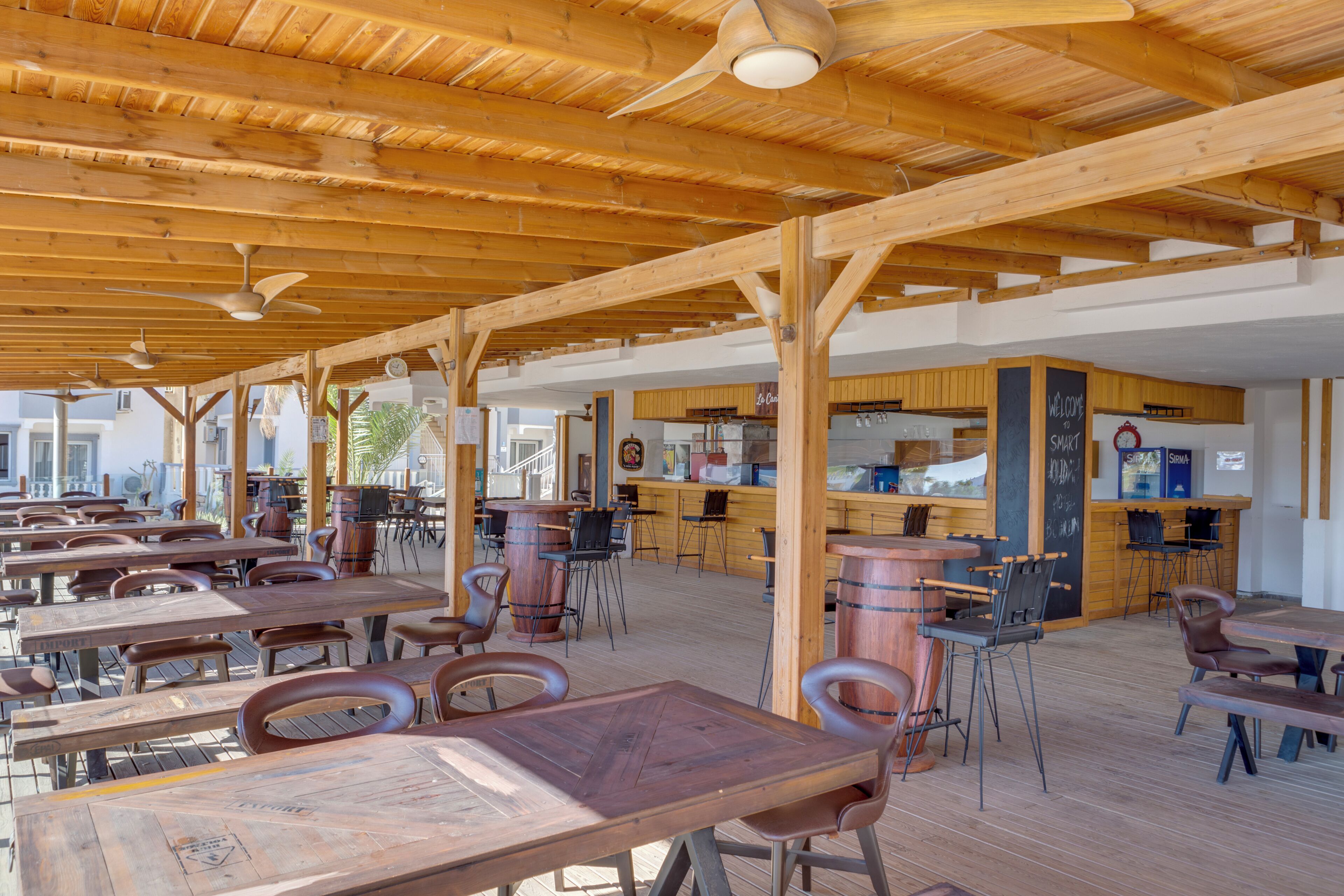 Een buiten eethoek met houten tafels en stoelen, een bar en een uitzicht op de stad.