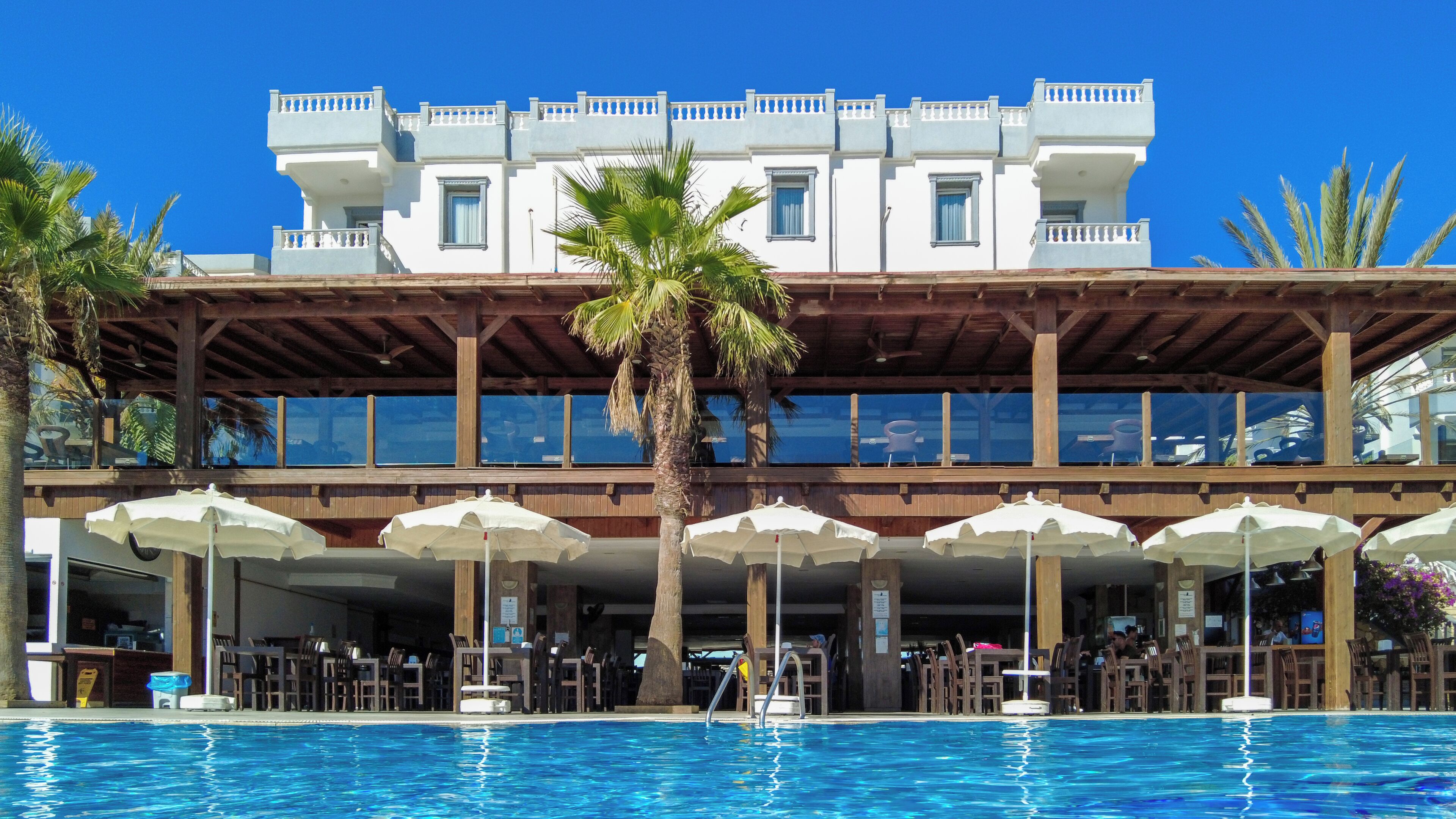 A hotel with a pool, outdoor seating, and a two-story building with balconies.
