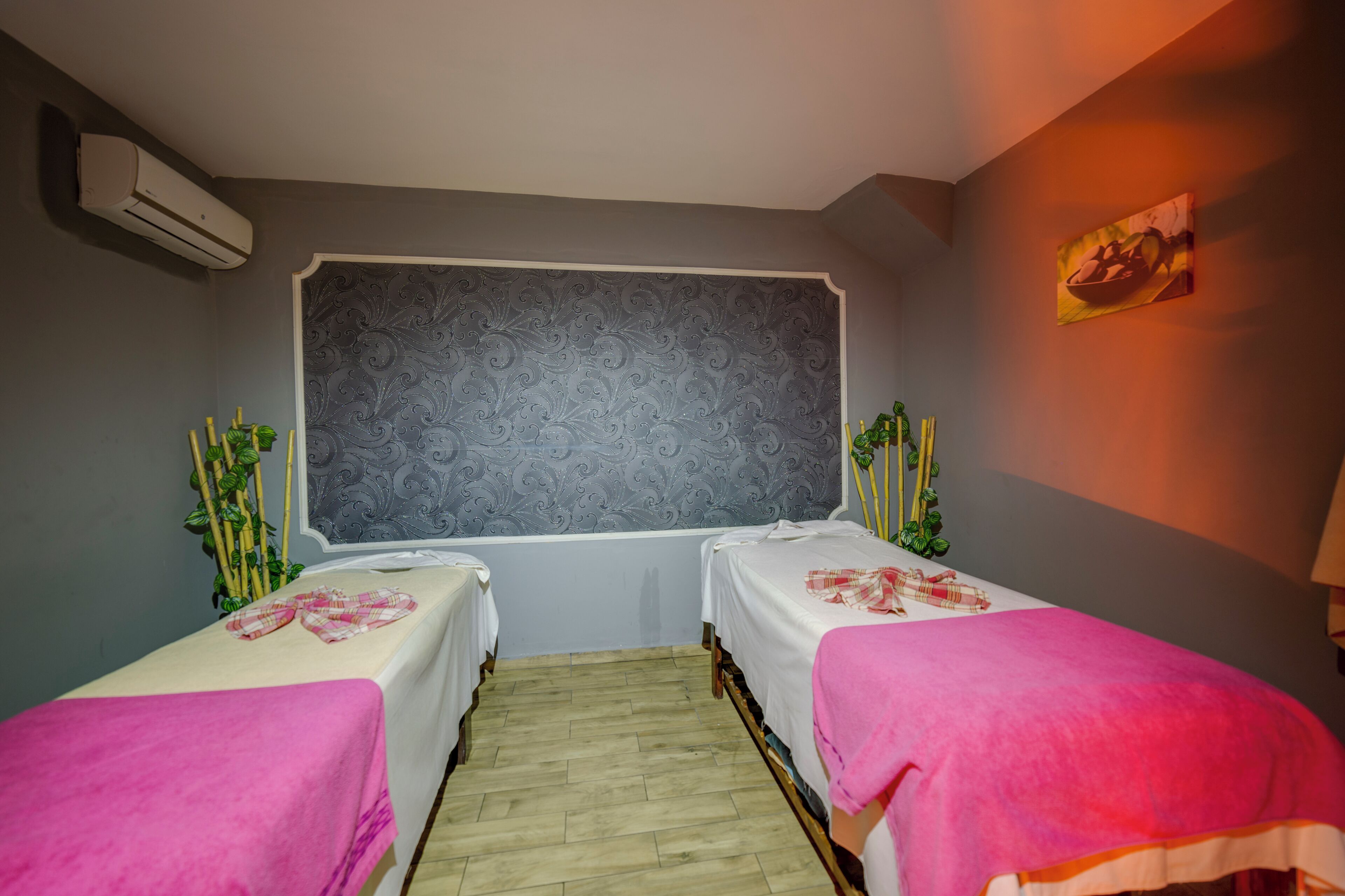 Une chambre avec deux lits, un mur décoré de motifs, un climatiseur et un tableau accroché au mur.