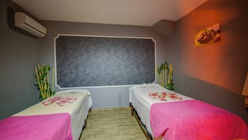 Une chambre avec deux lits, un mur décoré de motifs, un climatiseur et un tableau accroché au mur.