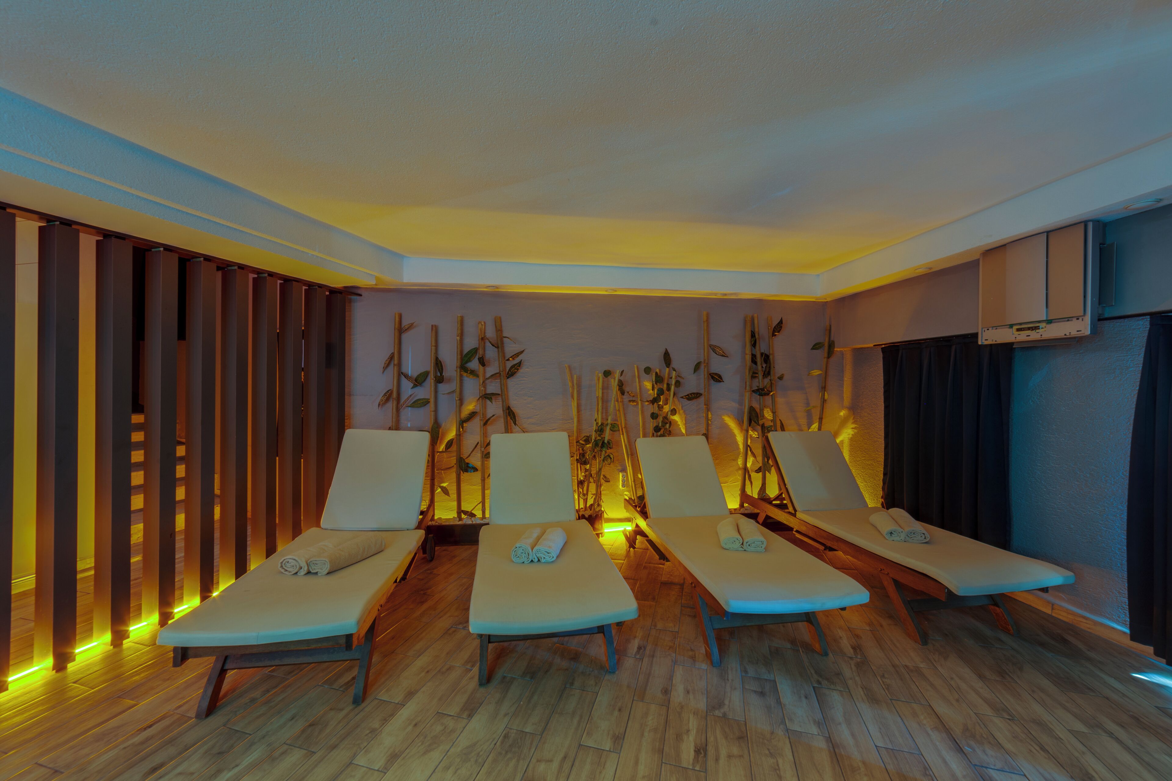 A room with four lounge chairs, wooden flooring, and a wall with vertical wooden slats.