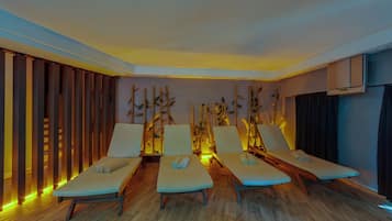 A room with four lounge chairs, wooden flooring, and a wall with vertical wooden slats.