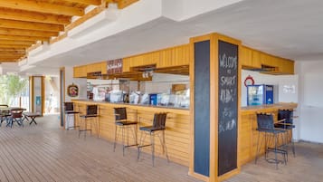A wooden bar area with bar stools, a chalkboard with 'WELCOME TO SMART' written on it, and a sign for 'The Coastal Pub'.