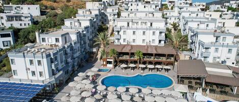 Ett hotell med en swimmingpool, flera balkonger och solstolar.