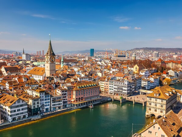 Ein weitreichender Blick auf eine historische Stadt mit einem markanten Turm und einem Fluss, der sich durch das Zentrum schlängelt.