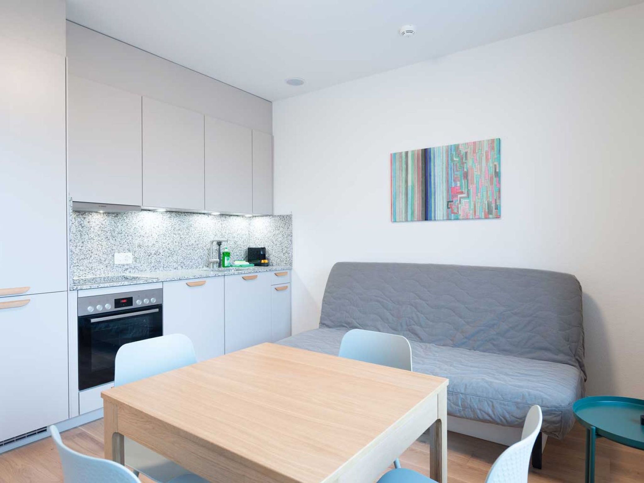 A compact living space with a kitchenette, a dining table, and a sofa.