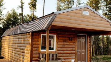 Eine Holzhütte mit Veranda, Bank und Tür.