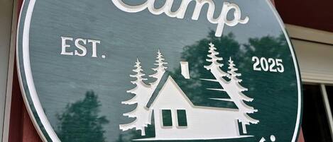 A circular sign with the text 'UpTah. Camp Bethel, ME. EST. 2025' and a cabin illustration.