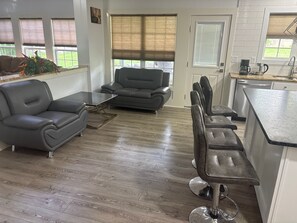 A living room with a sofa, a coffee table, and a bar area with stools. - Beautiful House in Nicholasville (Nicholasville)