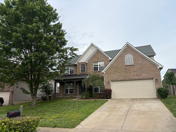A two-story house with a garage, a front yard, and a mailbox.