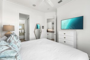 Ein Schlafzimmer mit Bett, Fernseher, Kommode und angrenzendem Badezimmer.