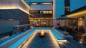 A courtyard with a fire pit, stone walls, and outdoor seating. - Qinghe Courtyard Jiuzhaigou (Ngawa Autonomous Prefecture)