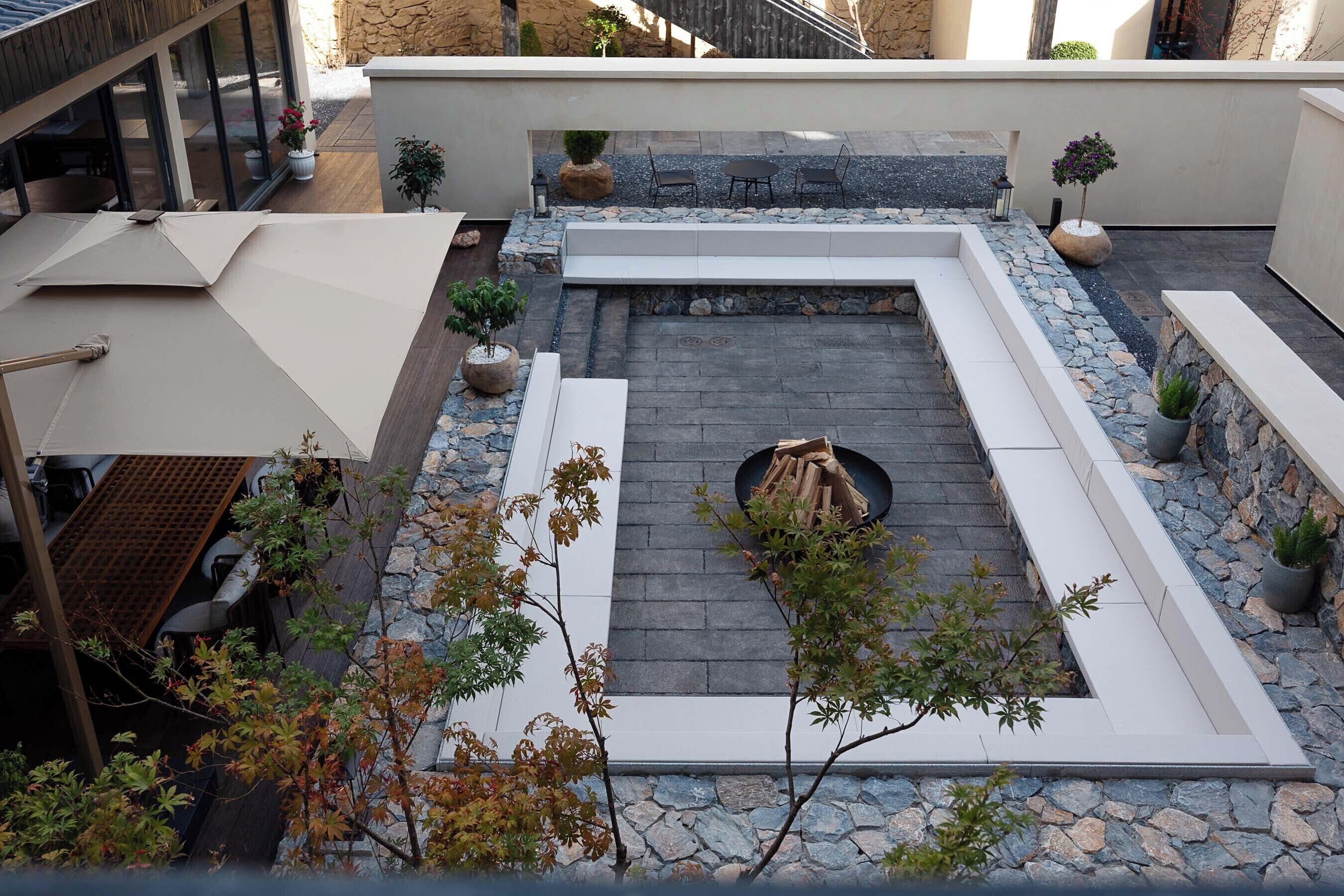 Una terraza en la azotea con un brasero, zonas de estar y plantas en macetas.