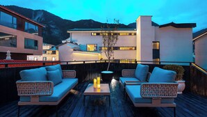 A rooftop terrace with wicker furniture, candles, and a view of a mountain. - Qinghe Courtyard Jiuzhaigou (Ngawa Autonomous Prefecture)