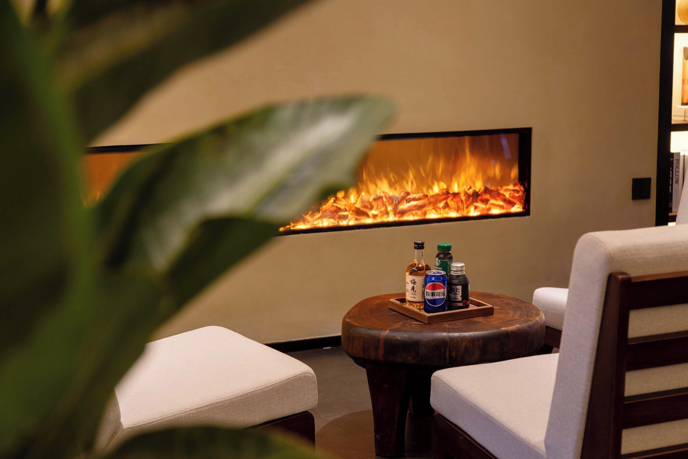 A cozy lounge area with a fireplace, seating, and a tray with bottles.