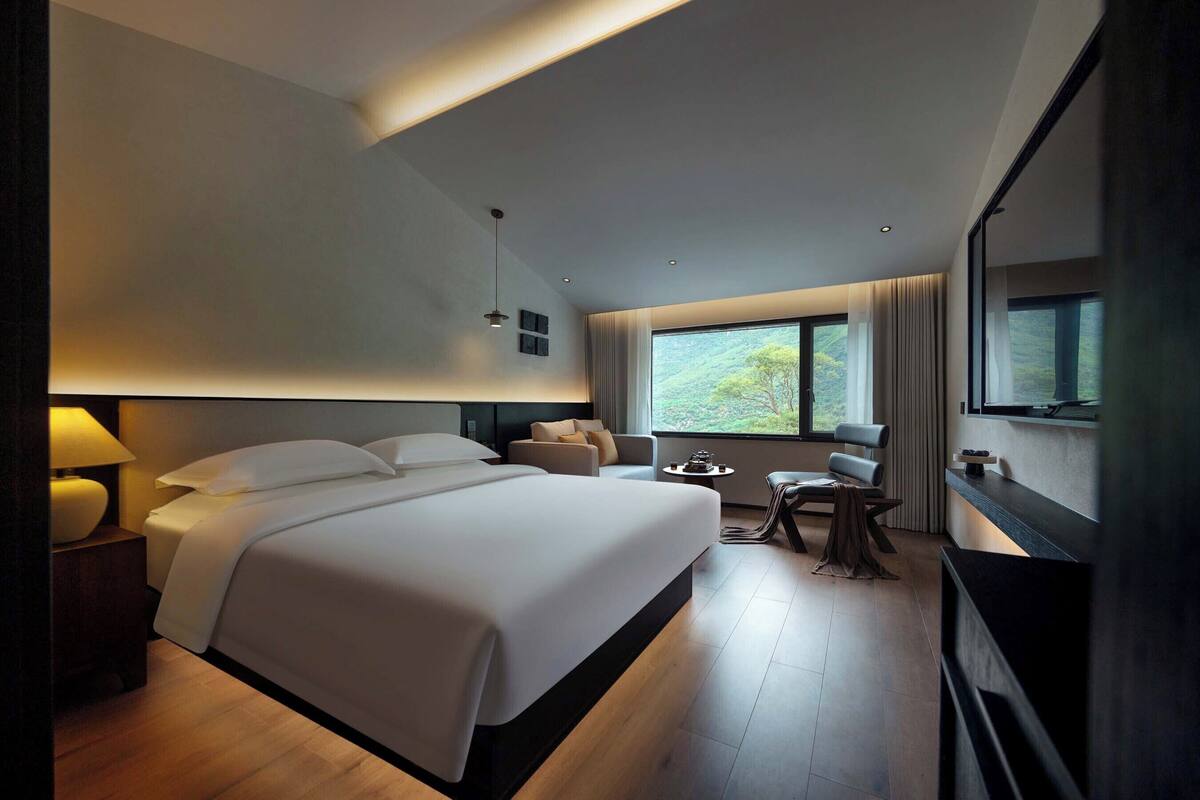 A modern hotel room with a large bed, a desk, and a TV.