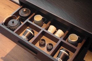 Un tiroir compartimenté contenant une théière, des tasses et un moulin à café.