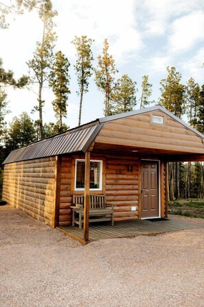 Eine Holzhütte mit Veranda, Bank und Tür.