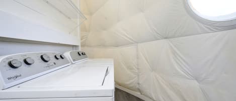 A laundry room with a Whirlpool washer and dryer, a metal shelf, and a window.