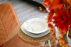 A glass table with a woven placemat, a white plate, and a clear glass setting.