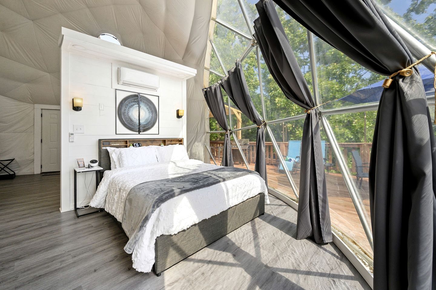 A spacious bedroom with a large bed, a ceiling fan, and a view through a large window with curtains.