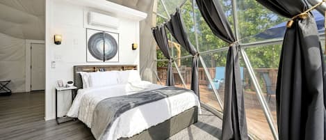 Un dormitorio amplio con una cama grande, un ventilador de techo y vistas a través de una ventana con cortinas.