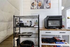 Una kitchenette con cafetera, tostadora, hervidor y un horno Cuisinart sobre una encimera blanca.