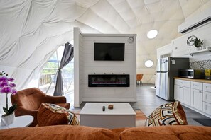 Alojamiento en tienda de campaña con televisión de pantalla plana, chimenea, comedor, cocina y vistas por la ventana.