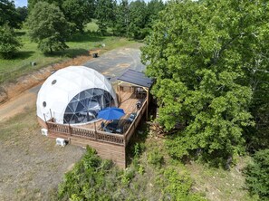 Een koepelvormige constructie met een terras en een klein gebouw met een schuin dak.