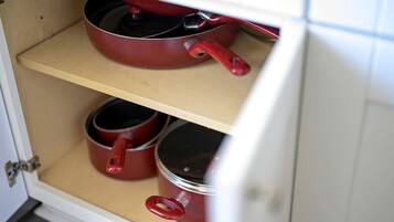Un armario de cocina con dos estantes, cada uno con utensilios de cocina rojos.