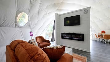 A tent-style room with a flat-screen TV, fireplace, and seating area.