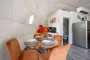 Een compacte keuken met een koelkast, een magnetron en een klein eethoekje met een tafel voor twee.