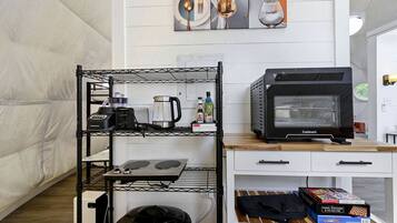 A kitchenette with a coffee maker, toaster, kettle, and a Cuisinart oven on a white countertop.