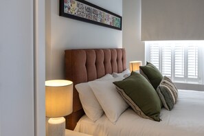 A neatly made bed with a tufted headboard, multiple pillows, and two bedside lamps.
