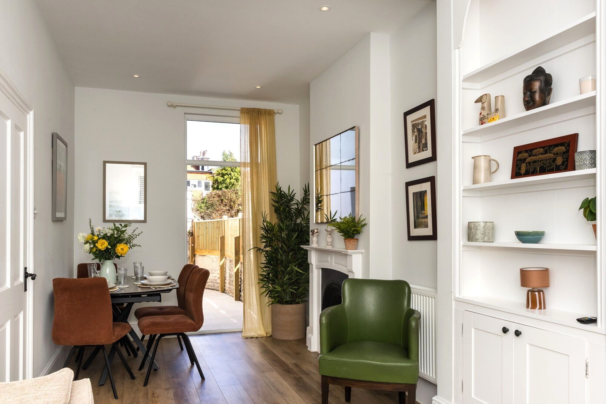 A well-lit room with a dining area, a green armchair, and a fireplace.