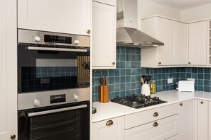 Eine Küche mit Backofen von Bosch, einem Herd und weißen Schränken.