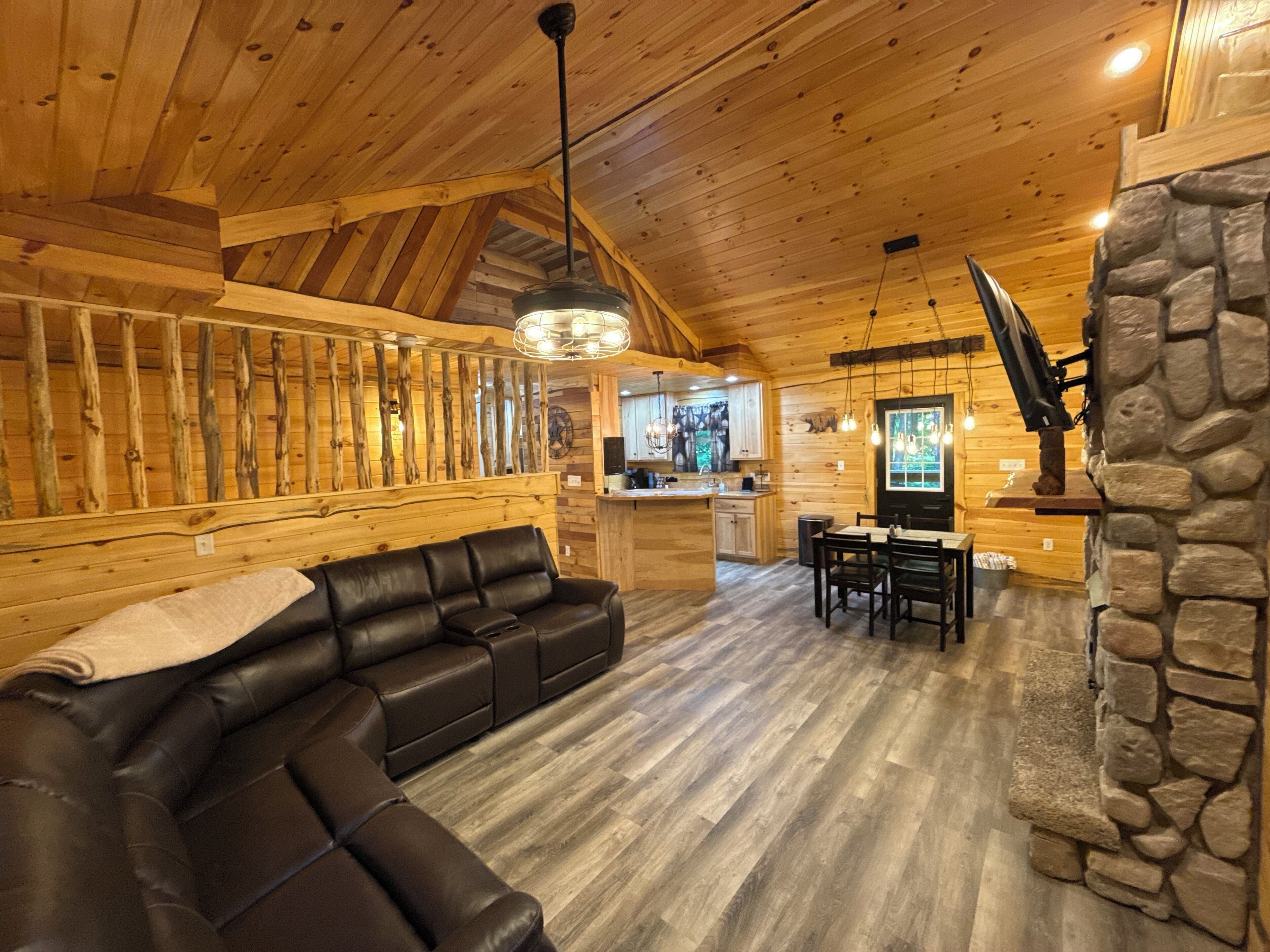 Un intérieur en bois avec un canapé en cuir, un mur en pierre et un coin cuisine.