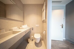 A modern bathroom with a toilet, a sink, and a towel rack. - Hotel BoxenStop (Dormagen)
