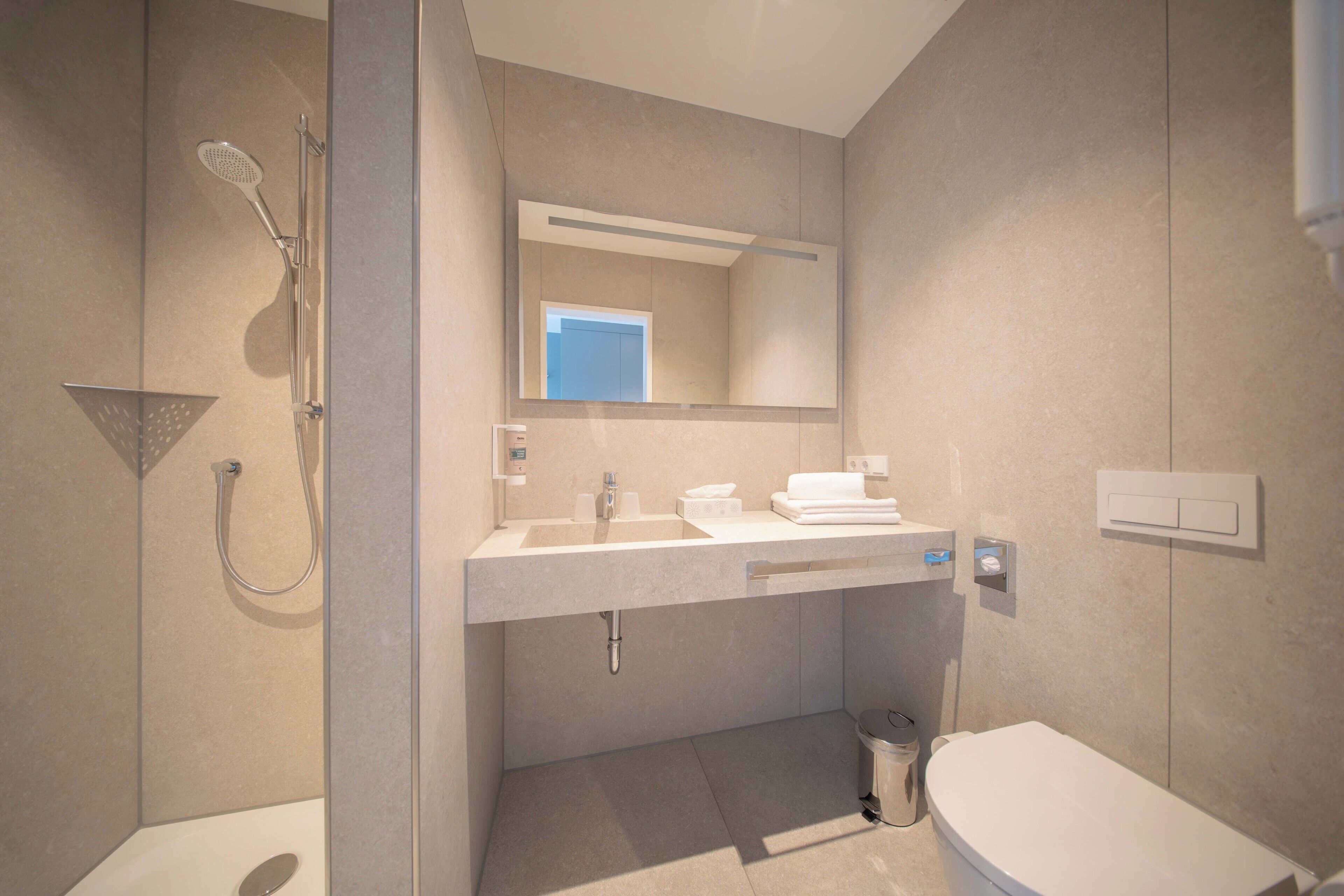 A modern bathroom with a shower, toilet, and sink.
