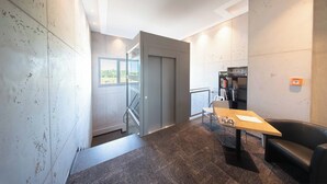 Un interior moderno con una escalera, una mesa con una computadora portátil, un sillón de cuero y una estantería.