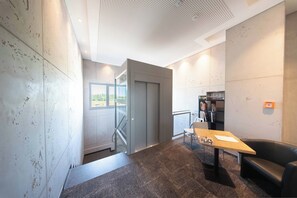 Un interior moderno con una escalera, una mesa con una computadora portátil, un sillón de cuero y una estantería.