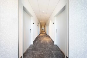 Un largo pasillo de hotel, con piso alfombrado y paredes blancas.