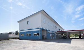 Ein Gebäude mit einer Garagentür, einer Tankstelle und wolkenlosem Himmel.