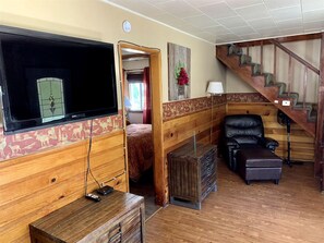 Ein Holzinterieur mit Fernseher, Bett, Stuhl, Treppe und Holzschrank.