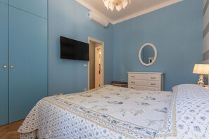 Ein Schlafzimmer mit einem Bett, einem Schminktisch, einem Spiegel und einem Fernseher an der Wand.