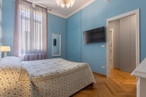 Ein Schlafzimmer mit Bett, Fernseher, Kleiderschrank und einem Fenster mit Vorhängen.