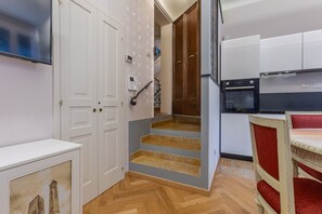 Eine moderne Küche mit weißen Schränken, einem eingebauten Backofen und einem roten, gepolsterten Stuhl.